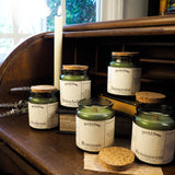 Collection of candles with labels on a wooden surface near a window