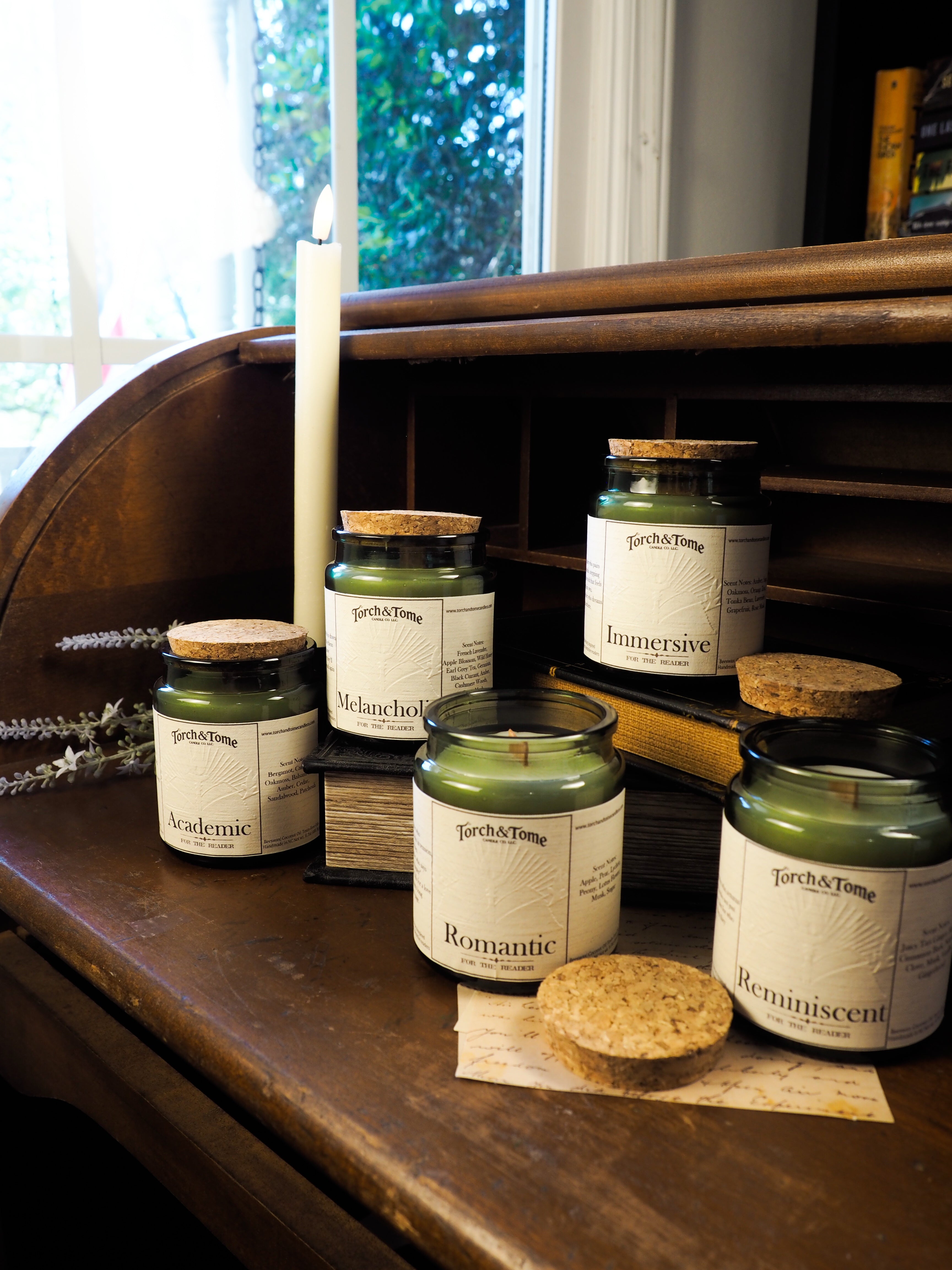 Collection of candles with labels on a wooden surface near a window
