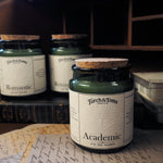 Candle jars with labels on a surface with books and papers
