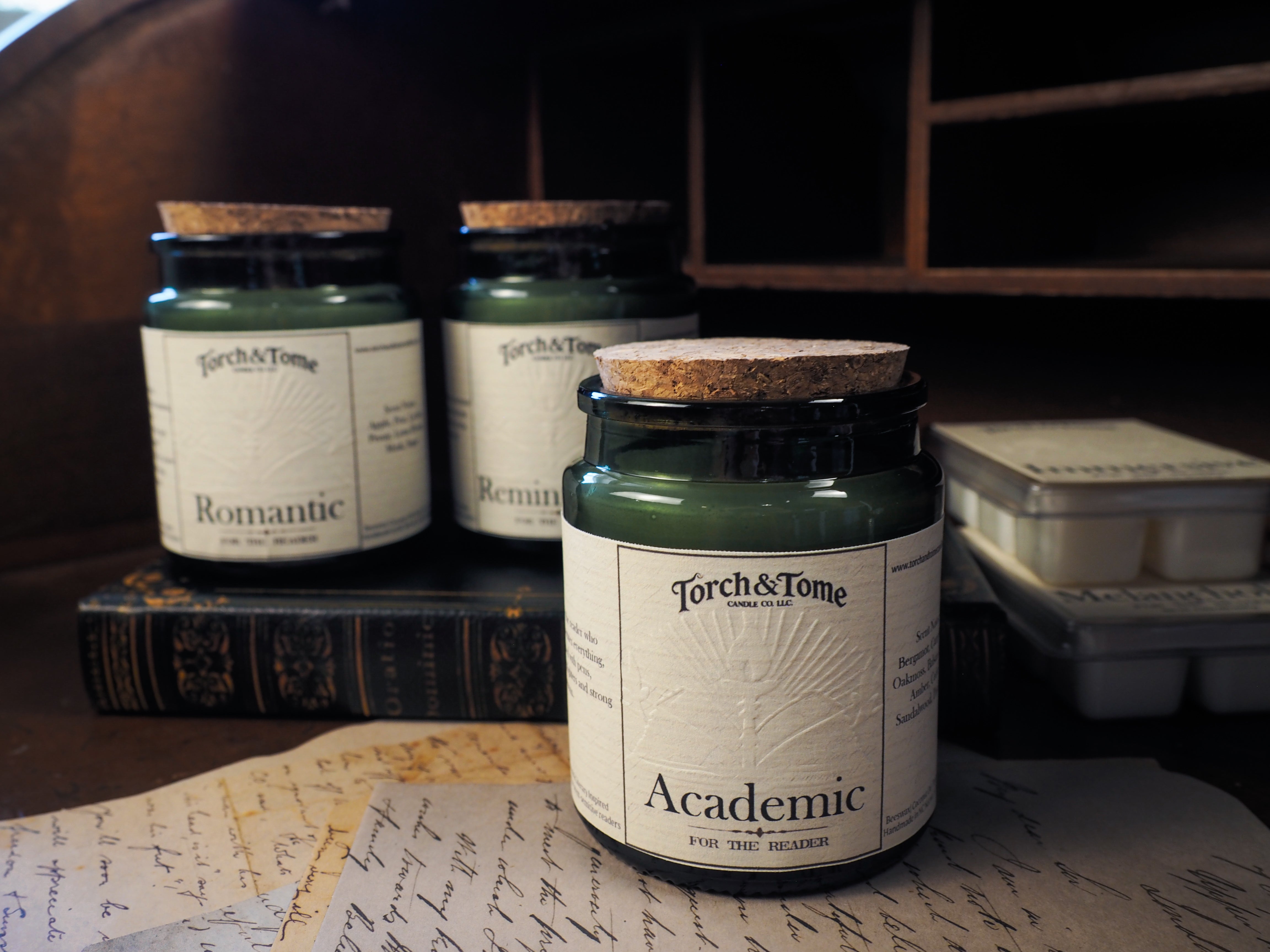 Candle jars with labels on a surface with books and papers
