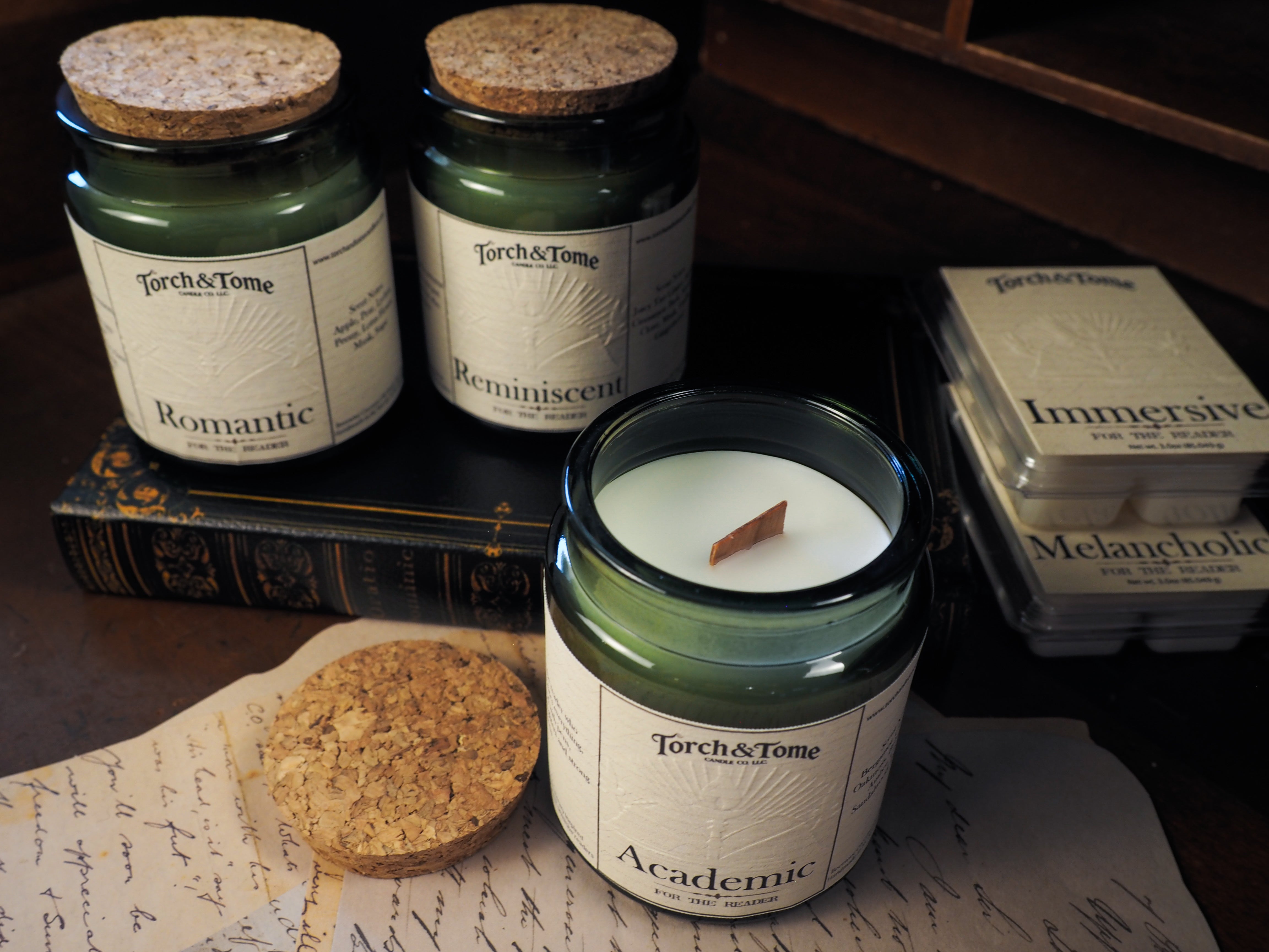 Candle jars with labels on a surface with books and papers