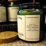 Candle jar with label on a textured surface, with other similar jars in the background.