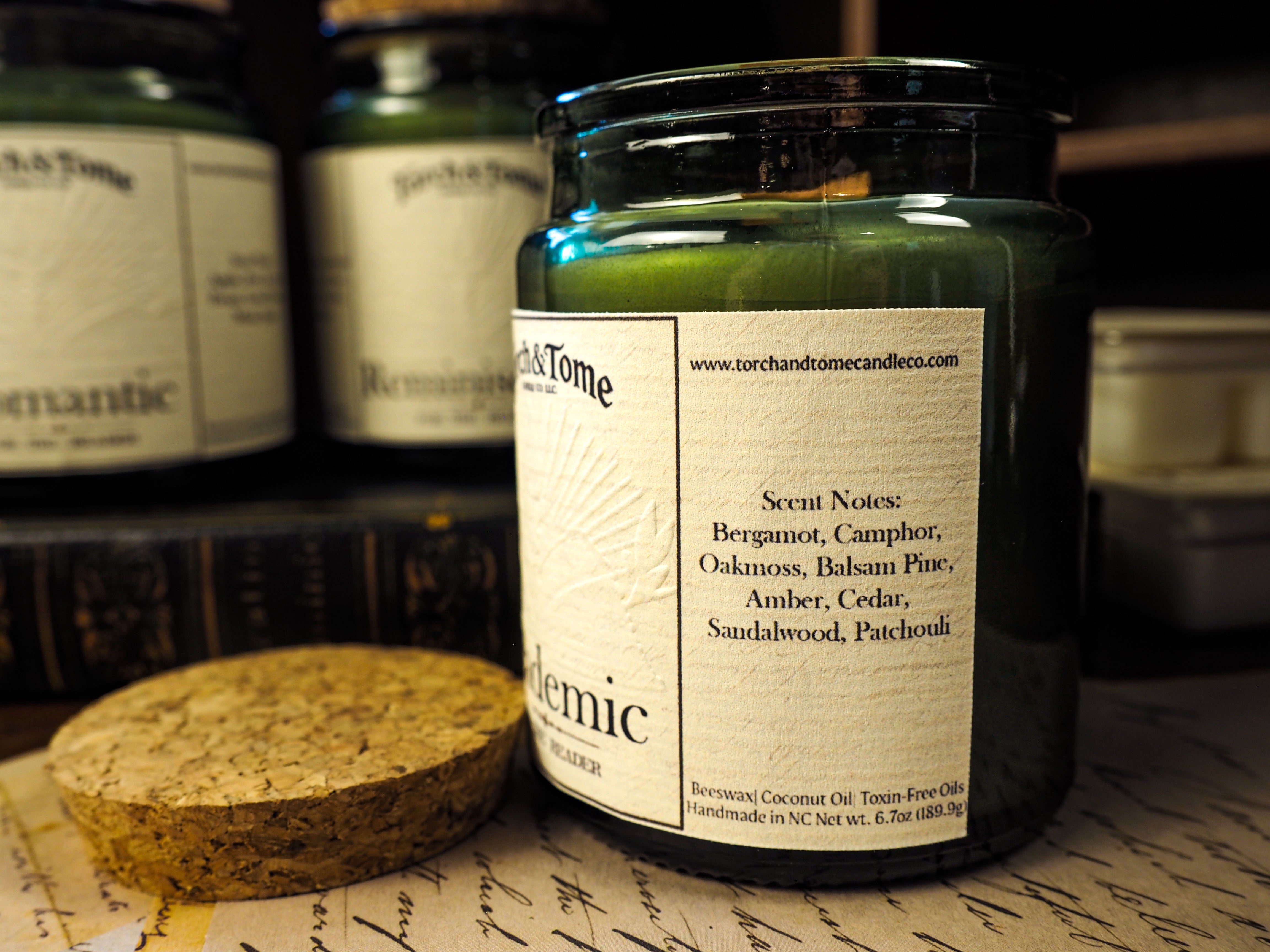 Candle jar with label on a textured surface, with other similar jars in the background.