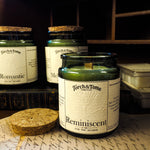 Three green glass candles sitting on a wooden desk, featuring cork lid and written notes on the tabletop