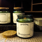 Three green glass candles sitting on a wooden desk, featuring cork lid and written notes on the tabletop