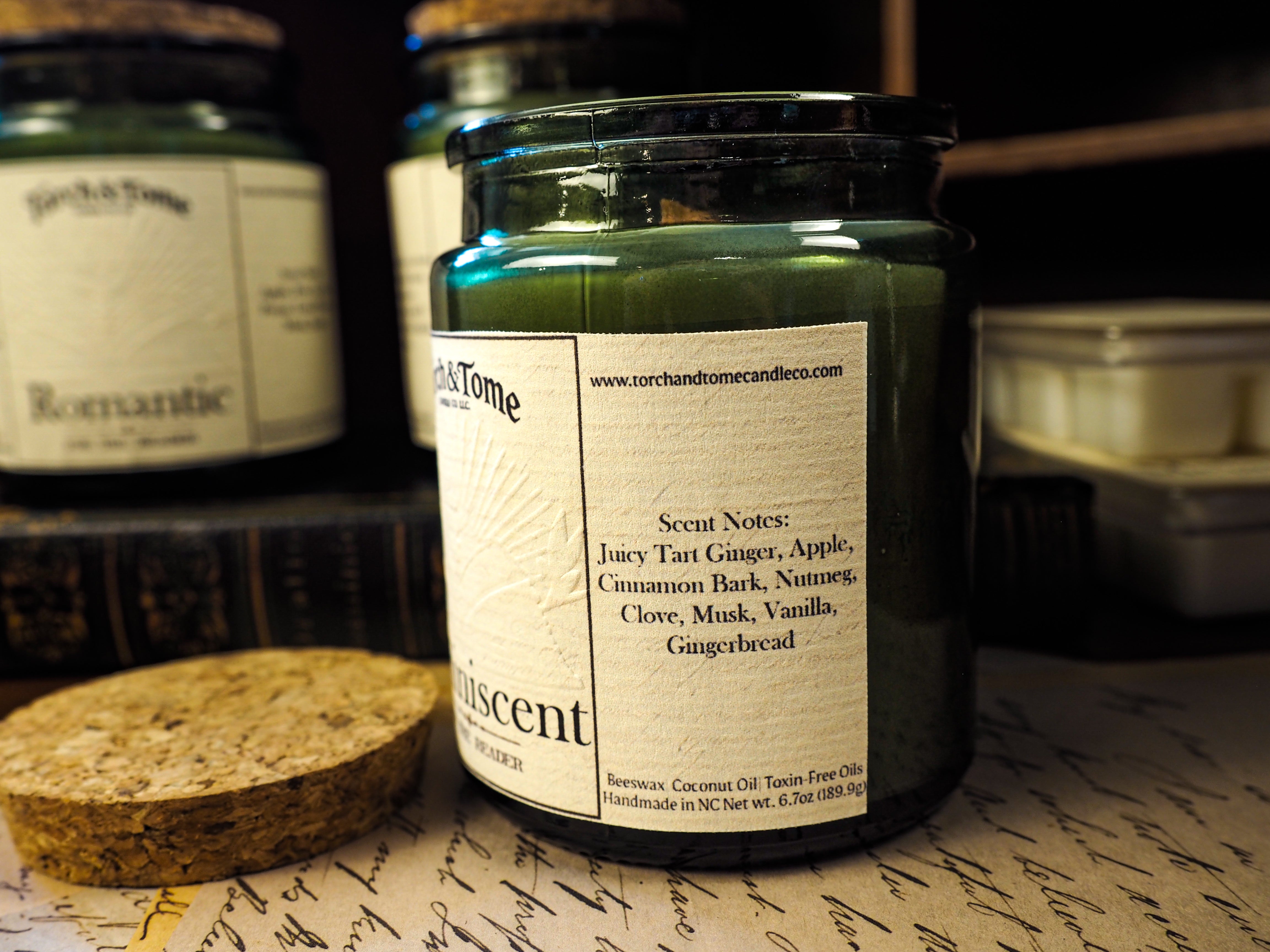 Candle jar with label on a surface with other candles in the background describing scent notes
