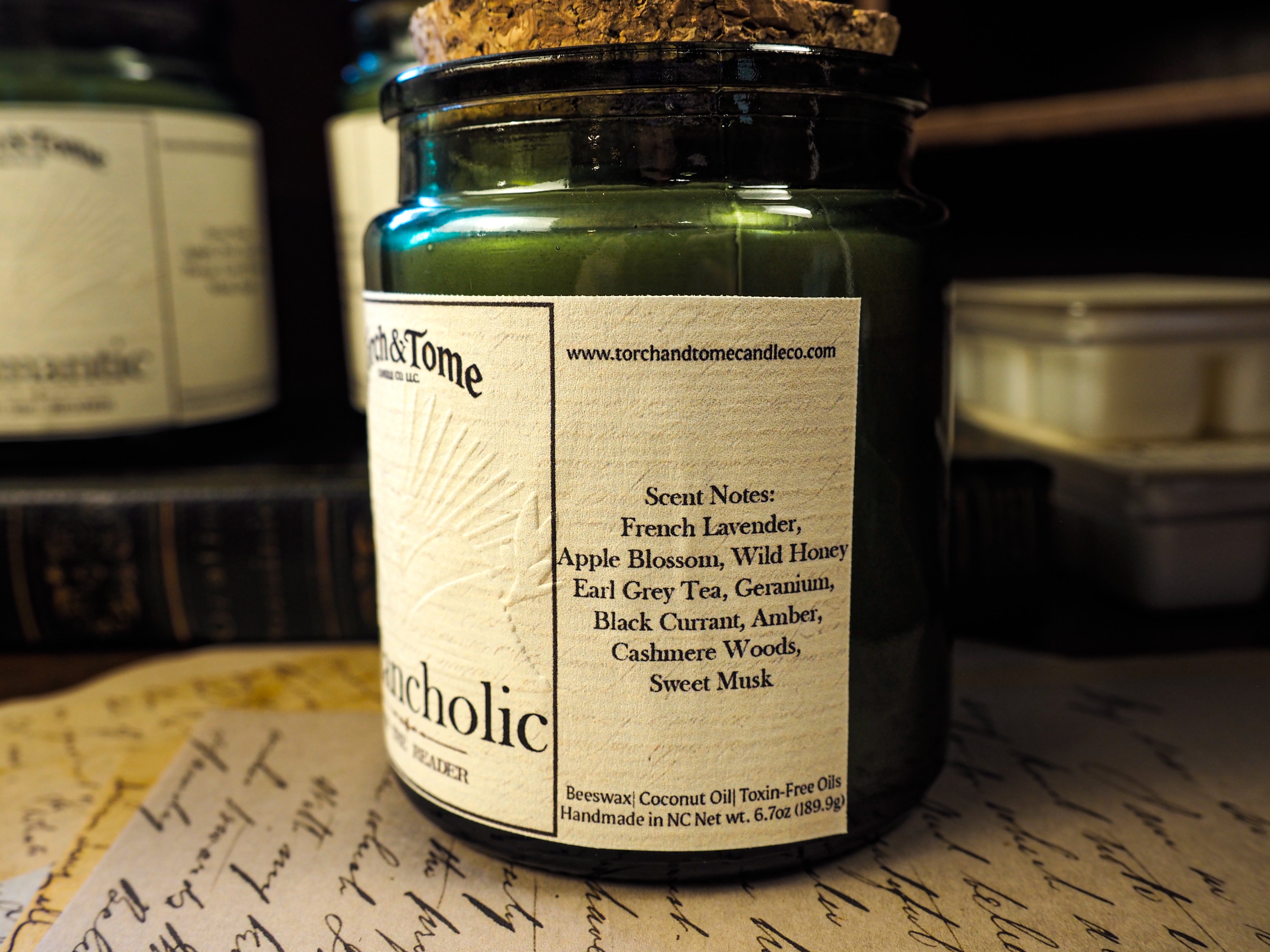 Candle jar with label on a surface with other candles in the background