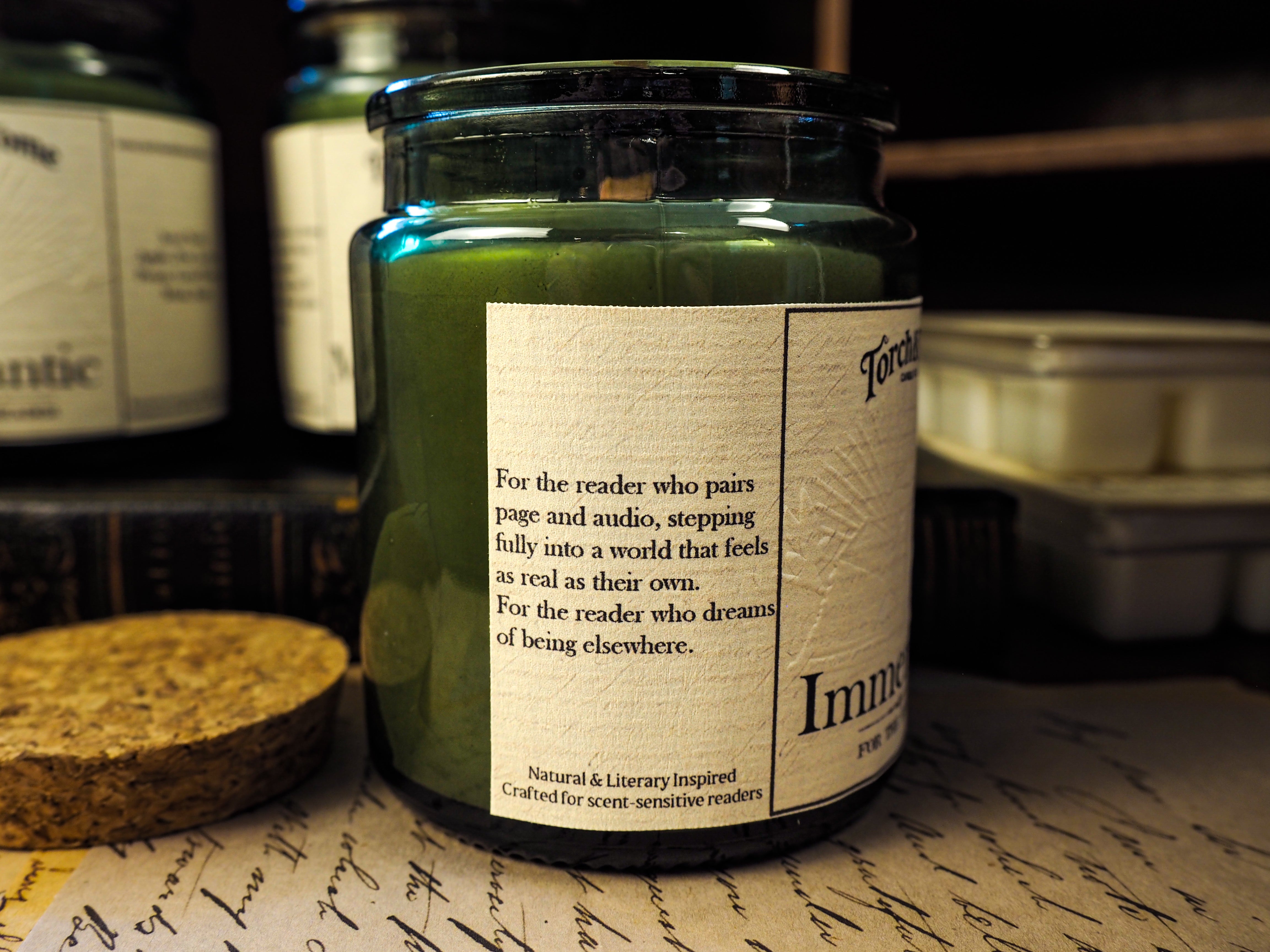 Candle jar with a label on a surface with other similar jars in the background