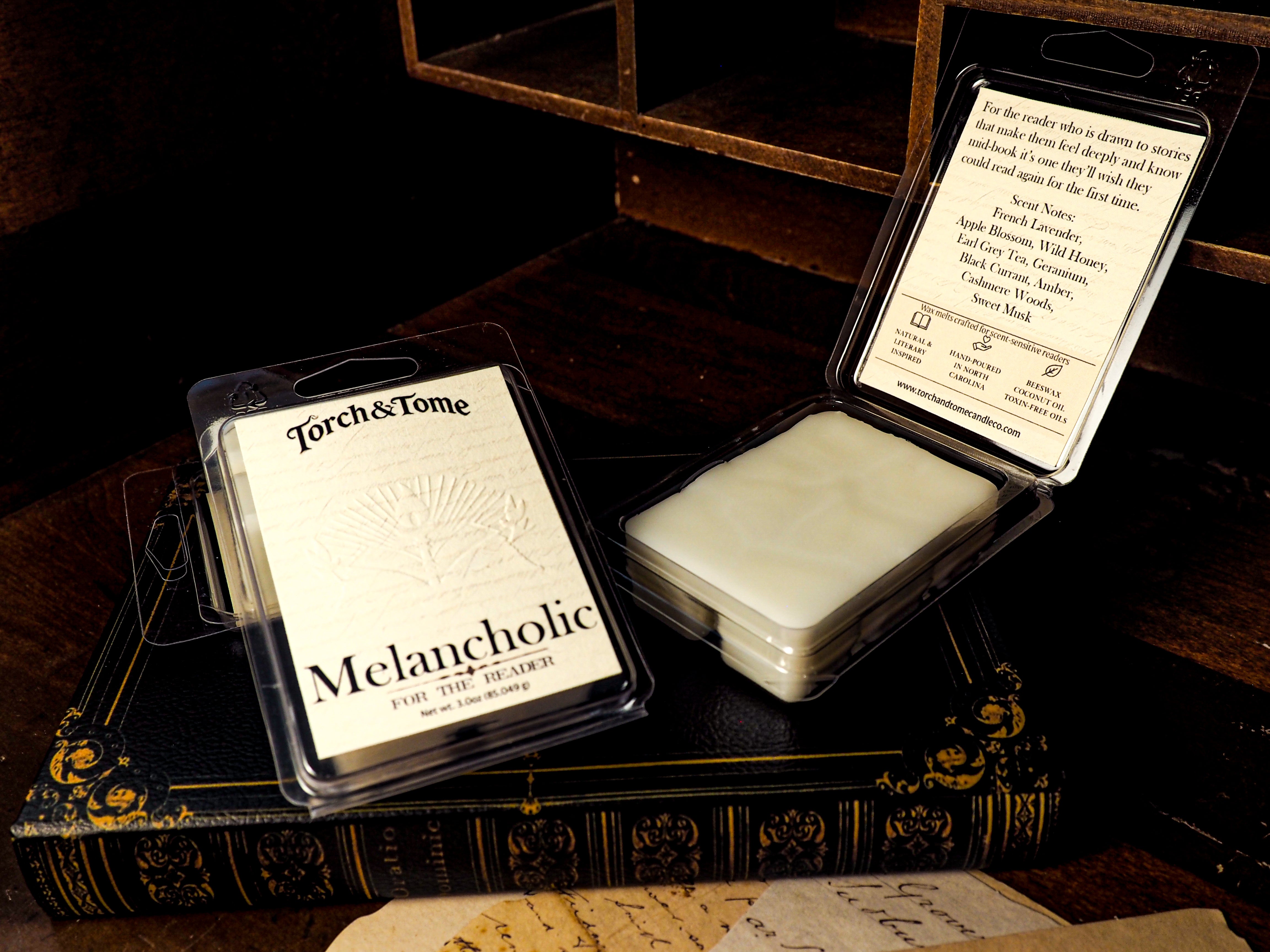 Torch & Tome Melancholic wax melts packaging on a dark surface with an open container.