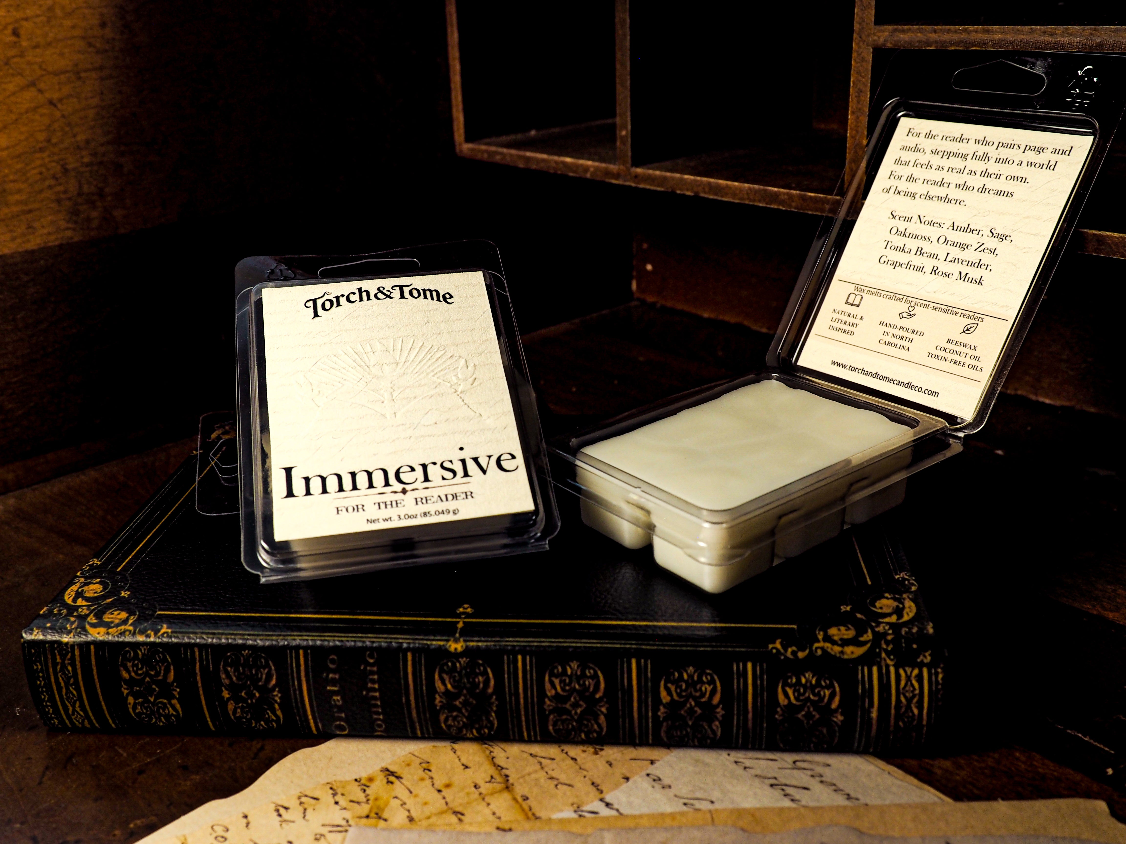 Torch & Tome Immersive wax melts packaging on an old book with a wooden surface.