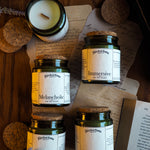 Collection of jars labeled 'Romantic', 'Melancholic', 'Immersive', and 'Academic' on a wooden surface with a candle and paper.