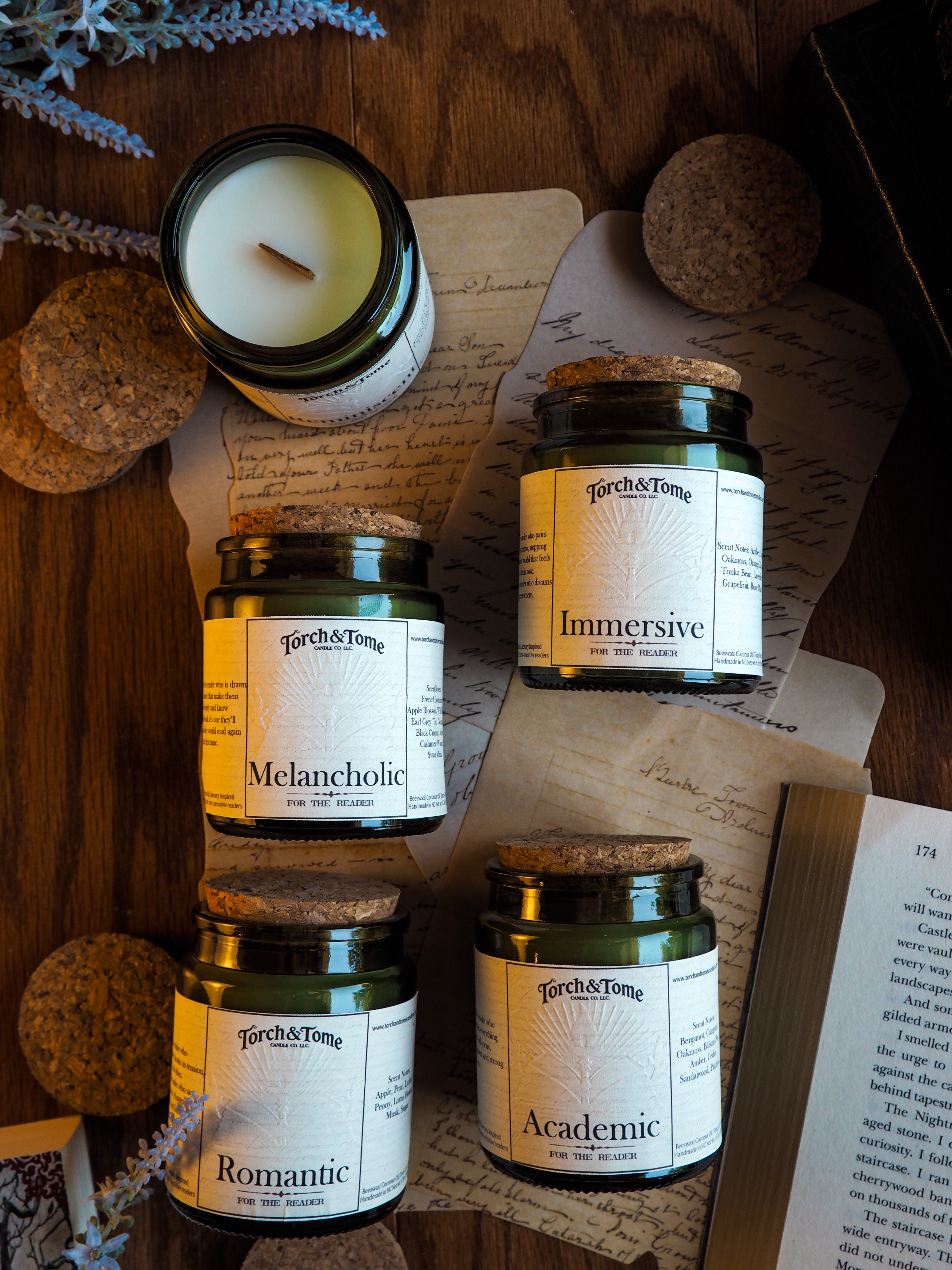 Collection of jars labeled 'Romantic', 'Melancholic', 'Immersive', and 'Academic' on a wooden surface with a candle and paper.