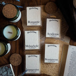 Collection of candles and waxmelts on a wooden surface with 'Torch & Tome' branding featuring an embossed logo on the parchment style label