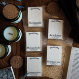 Collection of candles and waxmelts on a wooden surface with 'Torch & Tome' branding featuring an embossed logo on the parchment style label