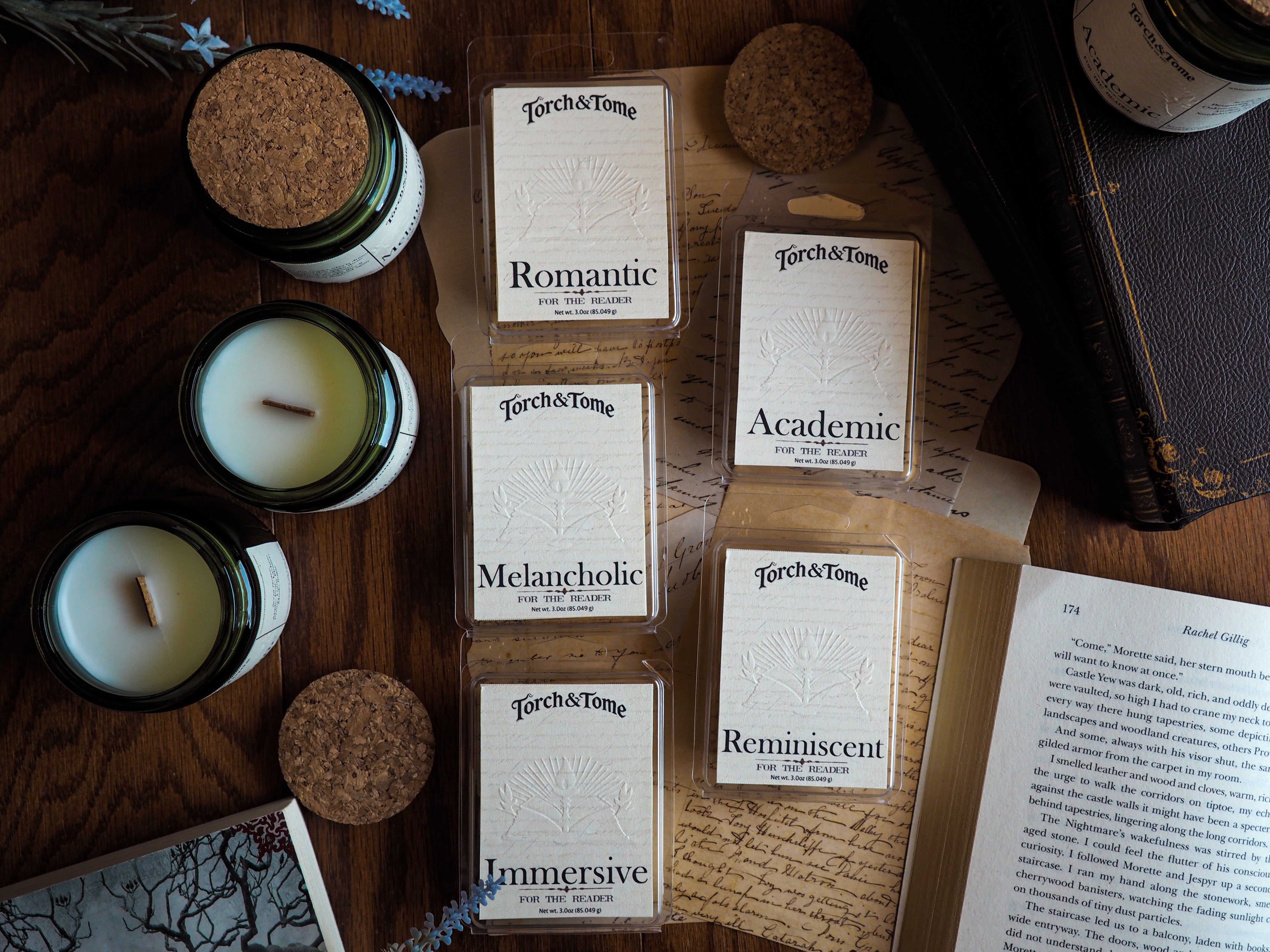 Collection of candles and waxmelts on a wooden surface with 'Torch & Tome' branding featuring an embossed logo on the parchment style label