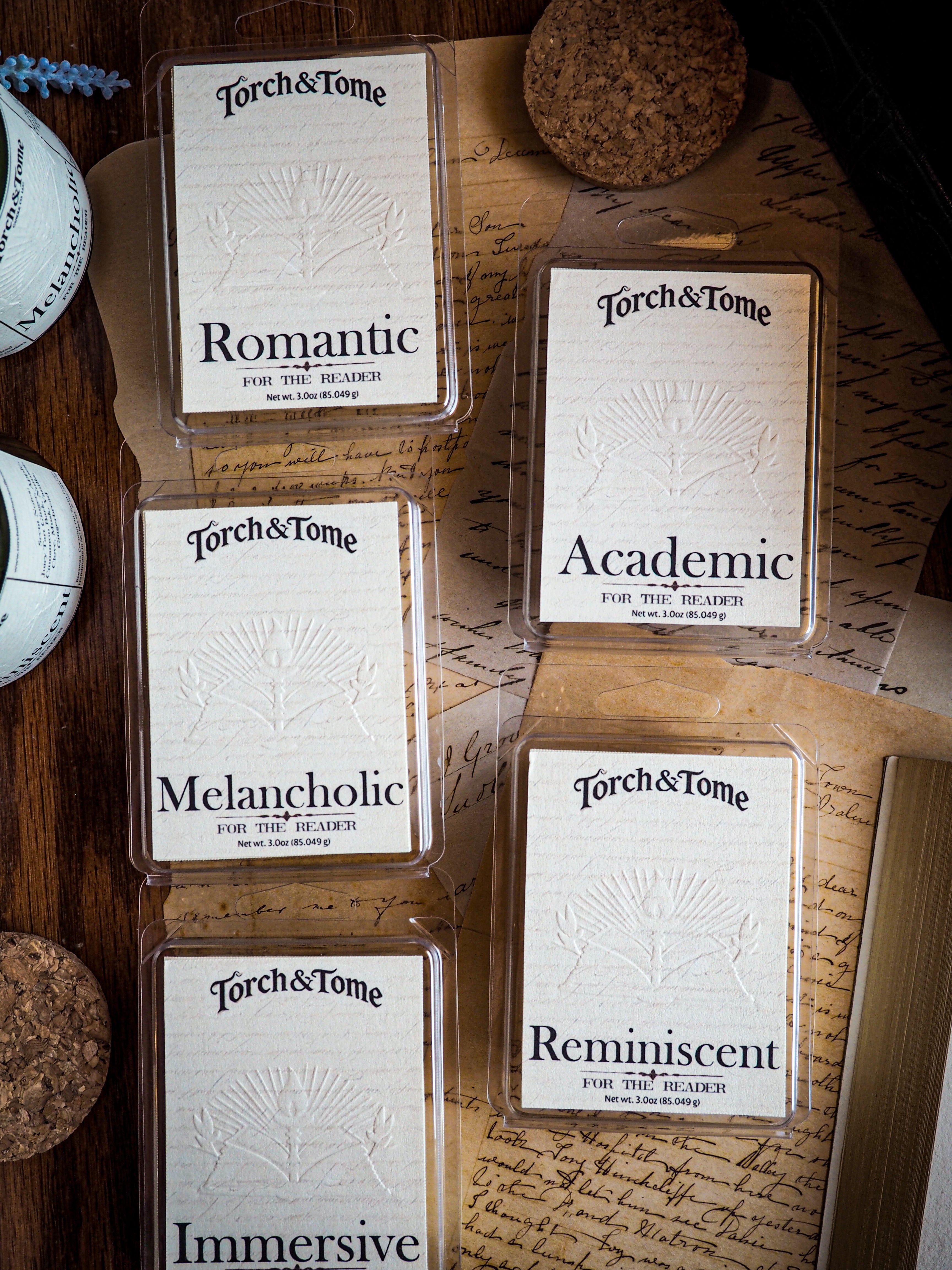 Collection of Torch & Tome waxmelts on a textured surface with visible branding.