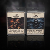 Two wax tarts (Syndicate Siren on the left, Midnight Mercenary on the right) in packaging with scent related designs depicted on the label on a dark smoky background
