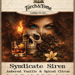 Closeup of the Syndicate Siren label. Featuring a woman with one blue eye and one green eye, a skull and black roses, with text about the candle's scent and ingredients. Ambered Vanille & Spiced Citrus scent notes.