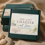 A dark green rectangular wax melt box with a large cream label reading 'THE LAST CHAPTER at Sea' is placed on a sandy surface with shells nearby. Three matching boxes are stacked behind it in a beach-like setting.